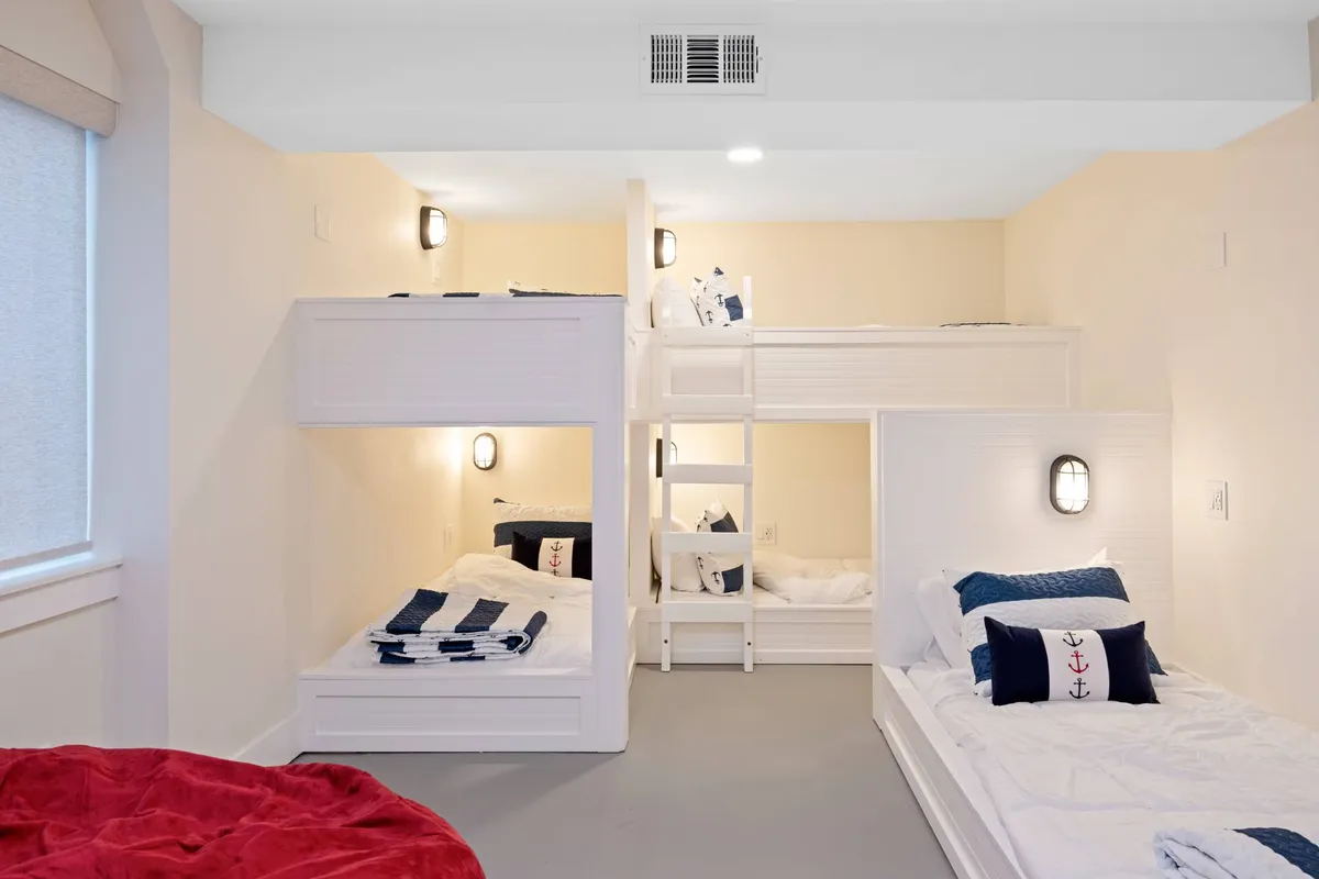 A playful bunk room decorated with nautical-themed accents, featuring sturdy bunk beds with soft bedding. The space feels welcoming for children or friends, with plenty of room for late-night chats and bonding.