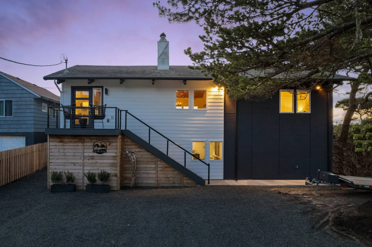 This exterior image showcases a welcoming deck area with a staircase, comfortable seating, and expansive windows overlooking a tree canopy. The scene radiates a cozy and tranquil atmosphere, perfect for watching sunsets or unwinding outdoors amid natural surroundings.